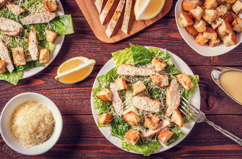 Homemade chicken caesar salad with cheese and croutons on a wooden table